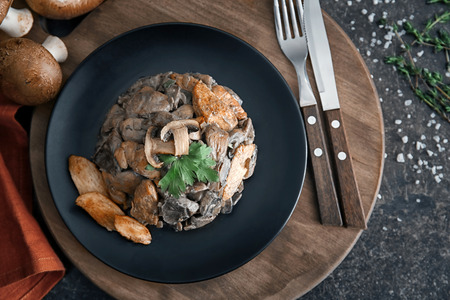 Plate with delicious mushrooms and meat on wooden boardの写真素材