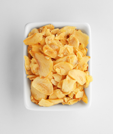 Dried garlic flakes in bowl on white backgroundの写真素材