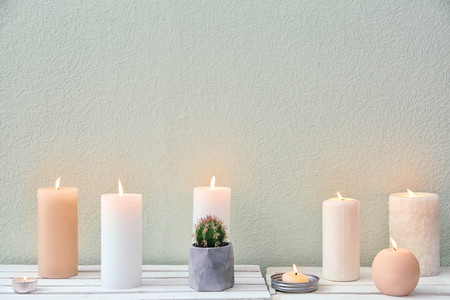 Beautiful burning candles on table against color backgroundの写真素材