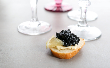 Tasty sandwich with black caviar and lemon on tableの写真素材