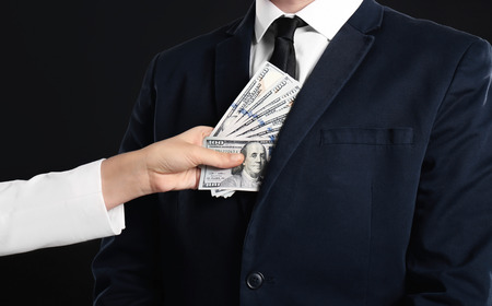 Woman putting bribe in businessman's pocket, closeup