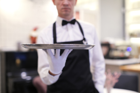 Waiter holding empty tray indoors, closeup