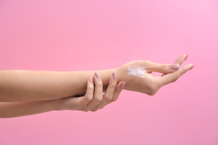 Woman applying hand cream on color backgroundの写真素材