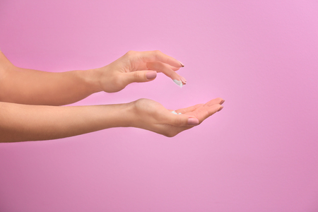 Woman applying hand cream on color backgroundの写真素材