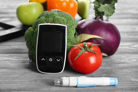 Digital glucometer, lancet pen and vegetables on table. Diabetes dietの写真素材