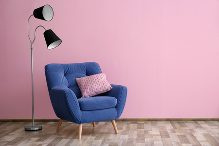 Soft armchair and floor lamp near color wallの写真素材