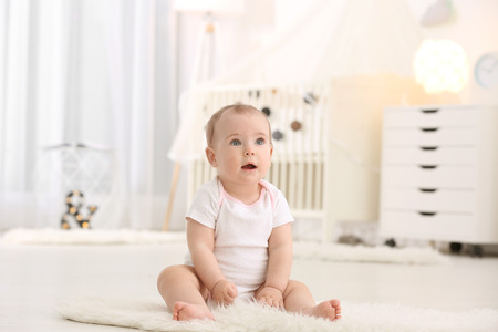 Cute little baby sitting on floor at homeの写真素材