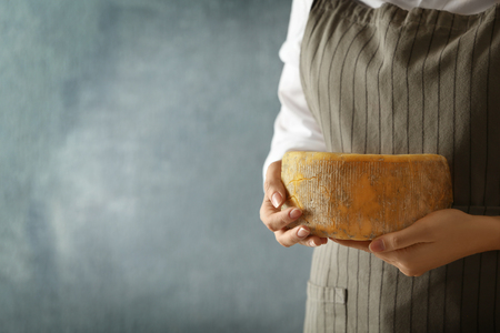 Woman holding delicious cheese on color background