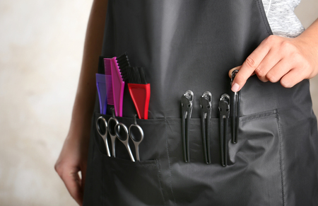 Woman in black apron with professional hairdresser set on light background, closeupの写真素材