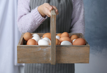 Woman holding wooden basket with chicken eggs, closeupの写真素材