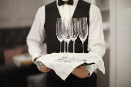 Waiter holding tray with glasses indoors, closeupの写真素材
