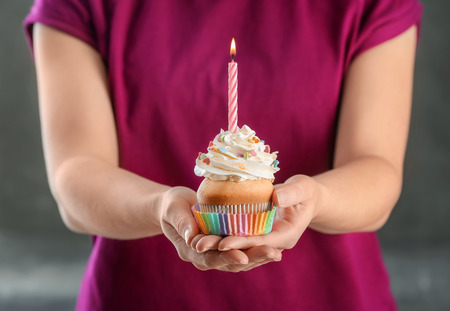 Woman holding cupcake with candle, closeupの写真素材