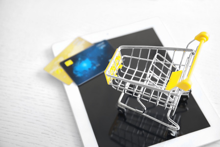 Tablet computer, small shopping trolley and credit cards on table, closeup. Internet shopping conceptの写真素材