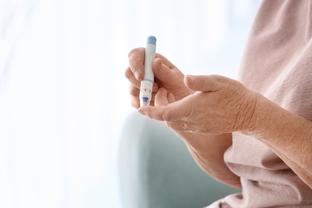 Elderly woman with diabetes measuring level of blood sugar at home, closeupの写真素材