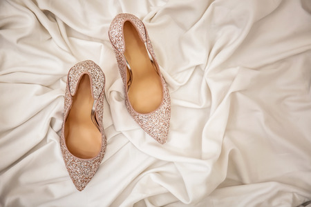 Pair of sparkly female shoes on white fabric, top viewの写真素材
