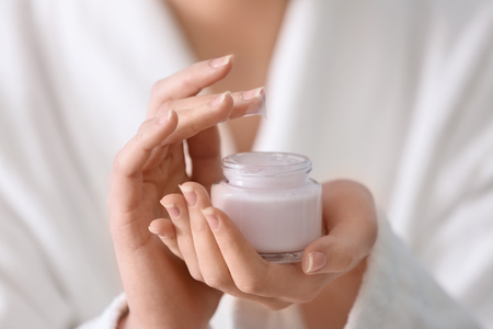 Young woman with jar of hand cream, closeupの写真素材