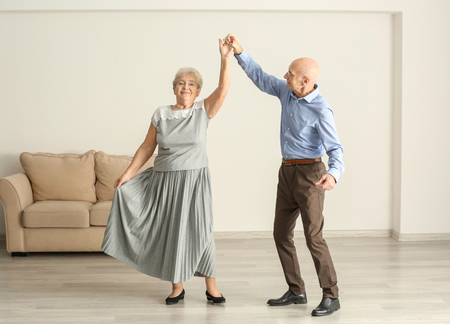 Cute elderly couple dancing at homeの写真素材