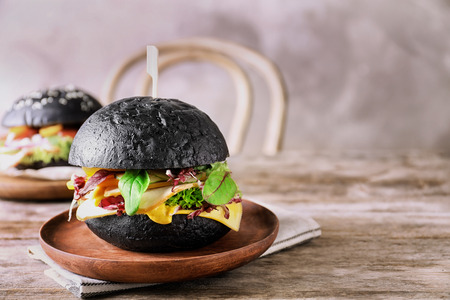 Plate with tasty black burger on tableの写真素材