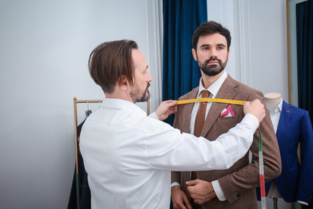 Tailor measuring client for custom made suit in atelierの写真素材