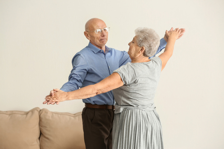 Cute elderly couple dancing at homeの写真素材