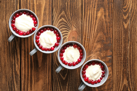 Cups with tasty vanilla pudding and cranberry on wooden background, top viewの写真素材