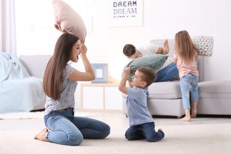 Happy family playing with pillows at homeの写真素材