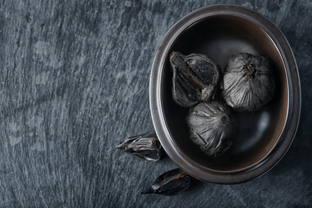 Bowl with black garlic (Allium sativum) on tableの写真素材