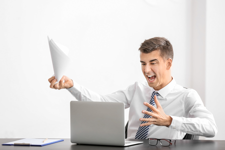 Young man in shirt using laptop at workplaceの写真素材