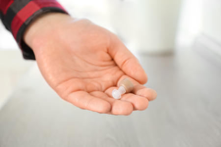 Man holding hearing aid on blurred background, closeupの写真素材