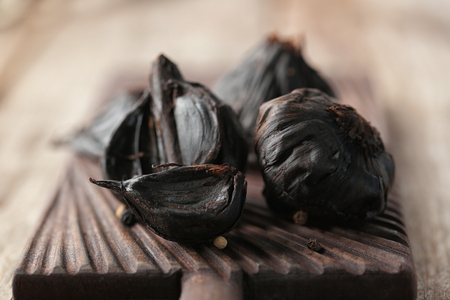 Black garlic (Allium sativum) on wooden boardの写真素材