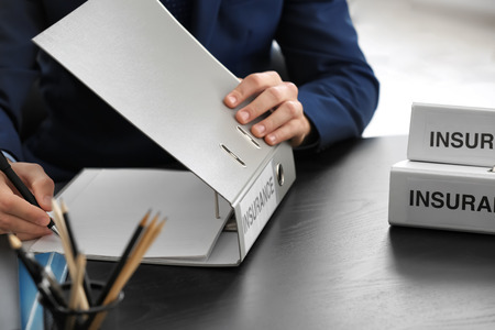 Insurance concept. Man with folders at tableの写真素材