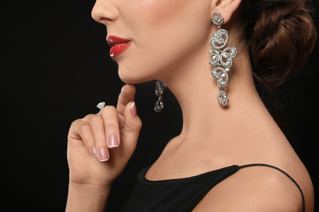 Beautiful young woman with elegant jewelry on dark background, closeupの写真素材