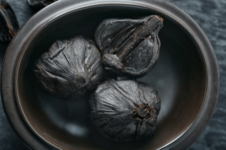 Bowl with black garlic (Allium sativum), closeupの写真素材