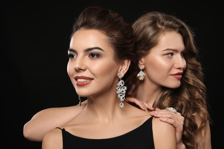 Beautiful young women with elegant jewelry on dark backgroundの写真素材