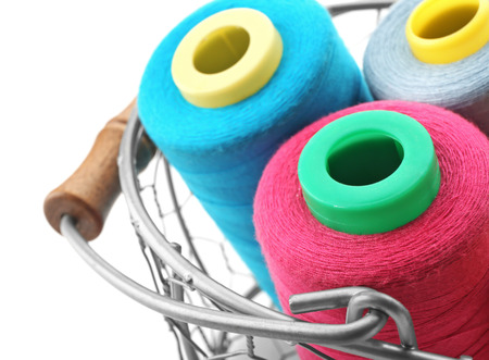 Metal basket with colorful sewing threads on white background, closeup