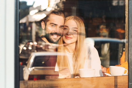 Young romantic couple in cafe, view from outdoors through windowの写真素材