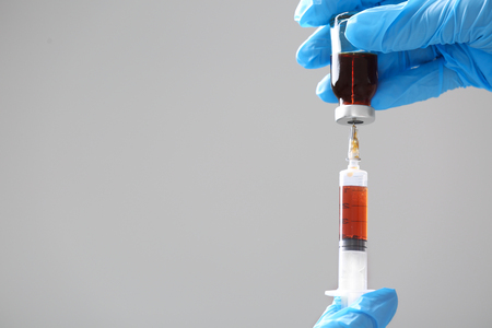 Doctor holding syringe and medicine for vaccination on color background, closeupの写真素材
