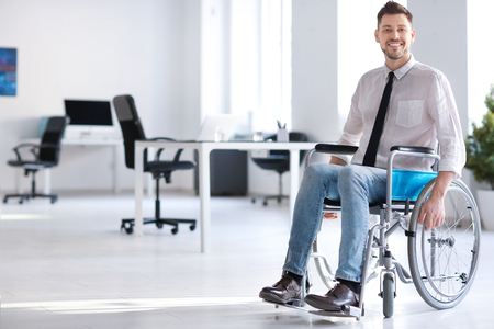 Young man in wheelchair at workplaceの写真素材