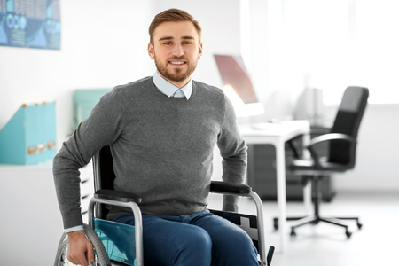 Young man in wheelchair at workplaceの写真素材