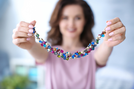 Young woman showing her beautiful necklace indoorsの写真素材