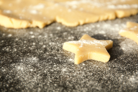 Cutting cookies from raw dough on table