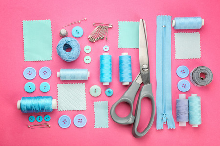 Different threads and sewing accessories on color background