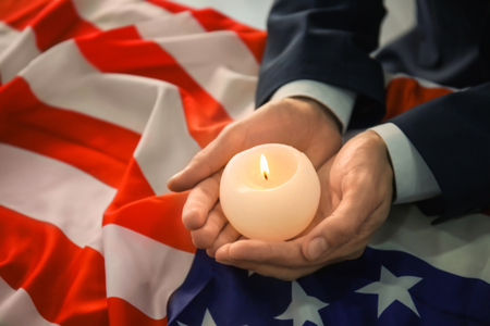 Man holding candle over American flag, closeupの写真素材