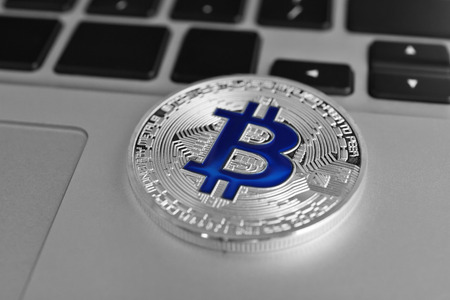 Silver bitcoin on laptop, closeup
