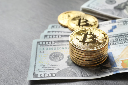 Golden bitcoins with dollar bills on tableの写真素材