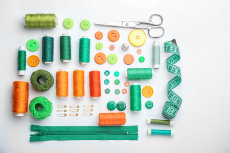 Colorful threads and sewing accessories on white background
