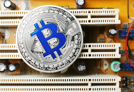 Silver bitcoin on PC circuit board, closeup