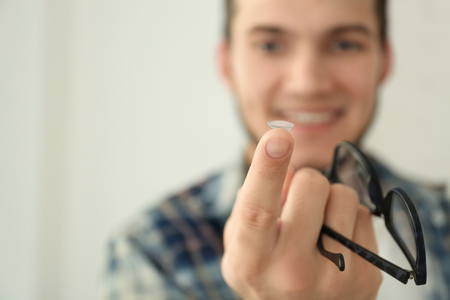 Man holding contact lens and glasses, closeupの写真素材