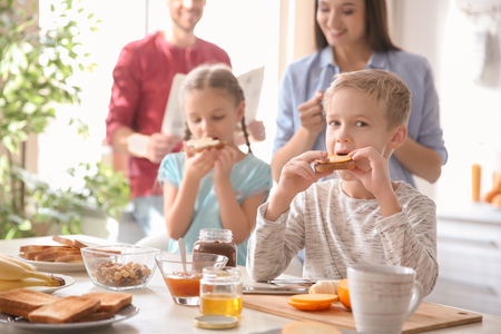Little children having breakfast with toasts in kitchenの写真素材