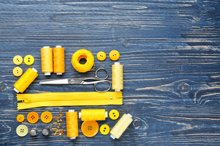 Colorful threads and sewing accessories on wooden background
